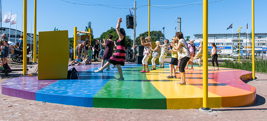 Flera personer dansar på regnbågsfärgad dansbana