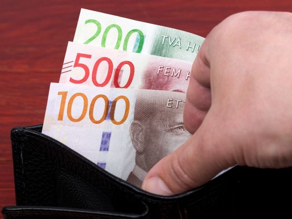 En hand visar sedlar i en plånbok. 1 700 kronor finns.