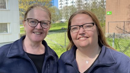 Två sjuksköterskor utomhus ler mot solen